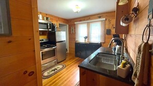 L’intérieur d’un chalet en bois comprend une cuisine équipée d’une cuisinière, d’un four, d’un réfrigérateur et d’un évier.
