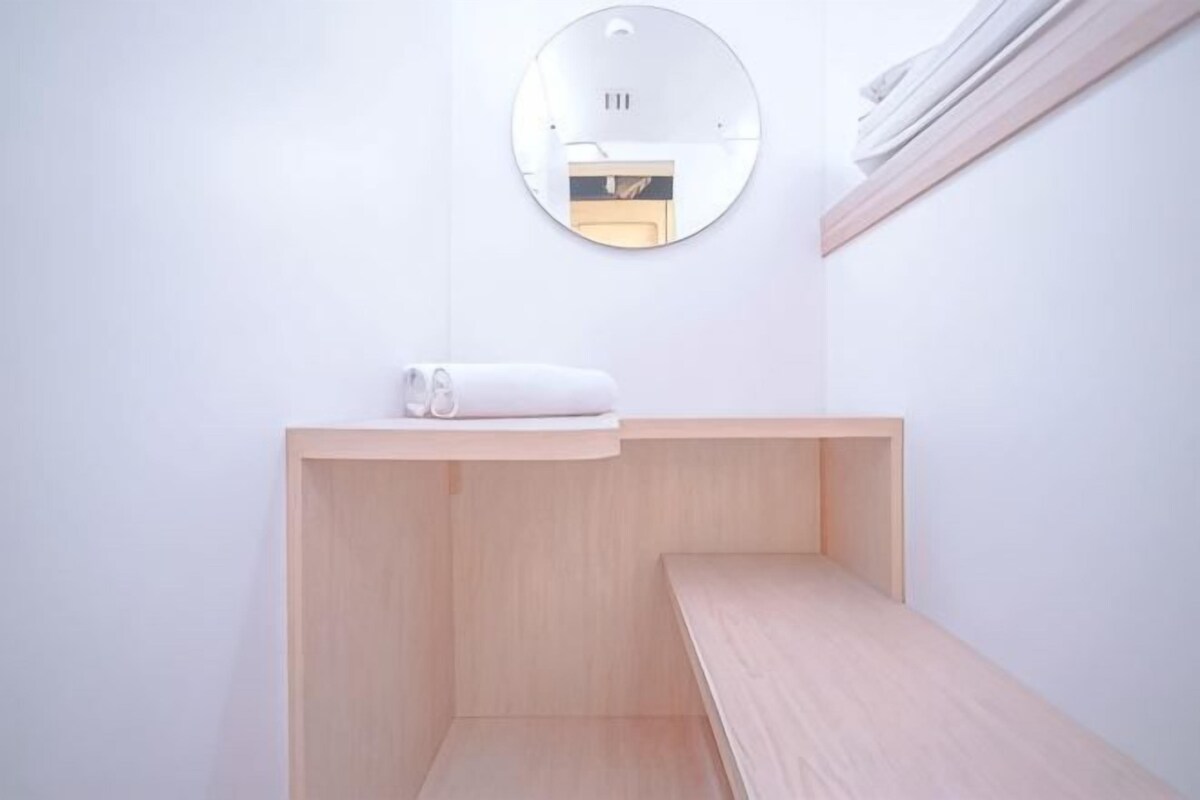 Un baño minimalista con un banco de madera, una toalla en un estante y un espejo en la pared.