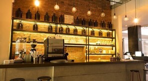 A bar area with a coffee machine, shelves of bottles, and hanging light bulbs. - Bobopod Cipaganti, Bandung (Bandung)