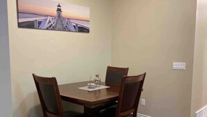 Ein Essbereich mit einem Holztisch und vier Stühlen, einem Bild einer Brücke an der Wand und einer Deckenleuchte.