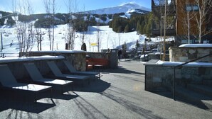 Une station de ski dotée de chaises longues, d’un mur en pierre et offrant une vue sur la montagne.