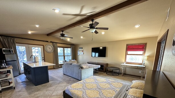 A spacious room with a large bed, a desk, a sofa, and a kitchenette. - Studio style guest house with Pool! (Georgetown)