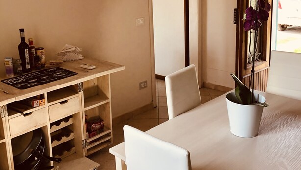 Un coin repas avec une table et des chaises, une petite cuisine équip ée d’un évier et de placards, et une porte donnant sur une autre pièce.