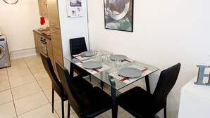Ein Essbereich mit einem Glastisch, schwarzen Stühlen und einer Uhr an der Wand.