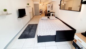 Ein modernes Schlafzimmer mit Bett, Fernseher, Schreibtisch und Spiegel.