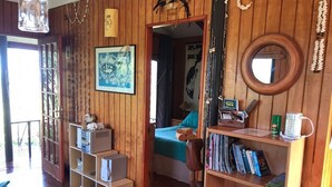 A wooden room with a bed, a bookshelf, and a desk. - Cabañas Mana Ora (Hanga Roa)