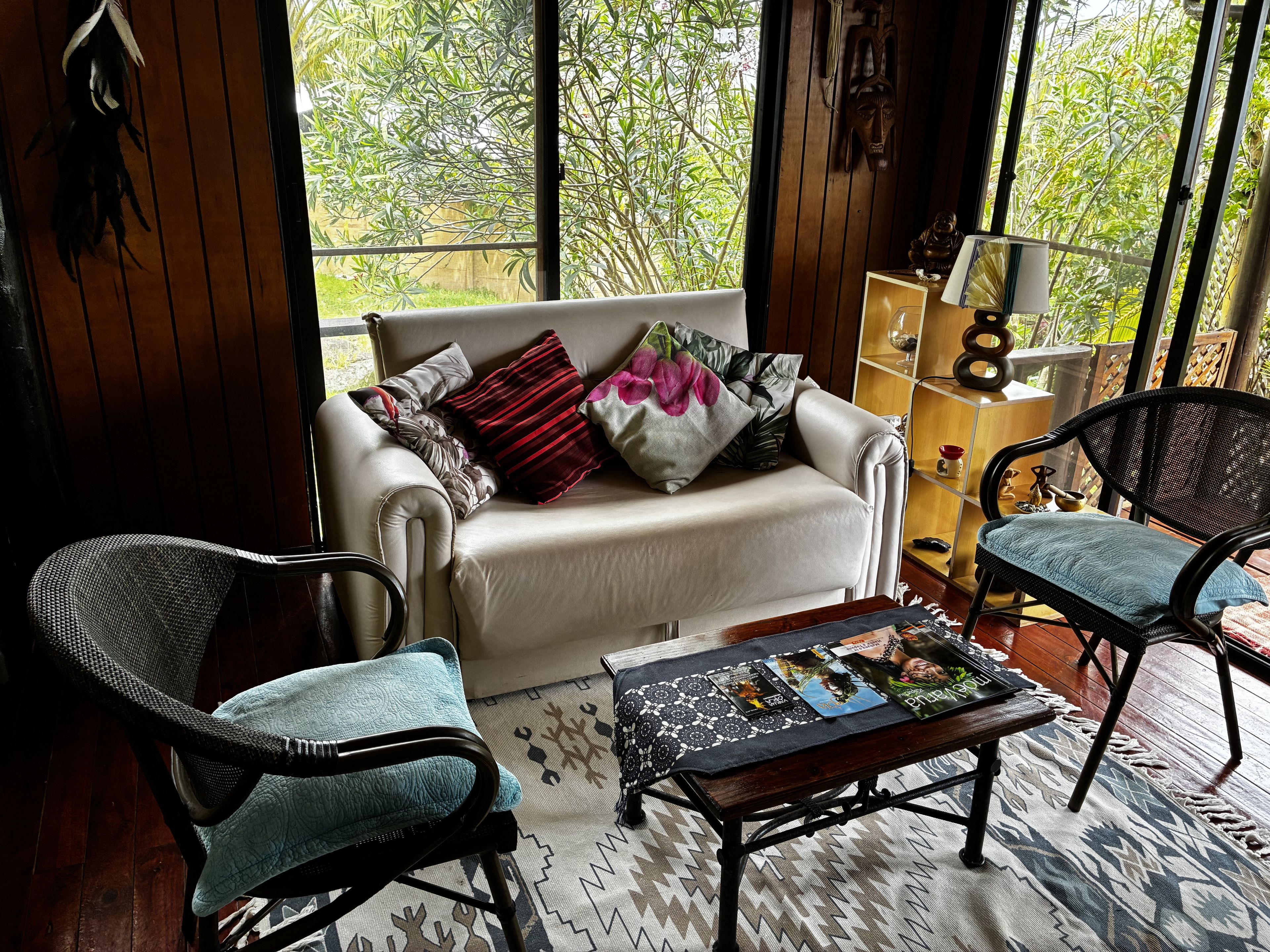 Un espacio de sala acogedor con un sofá, dos sillones, una mesita de centro y una estantería.