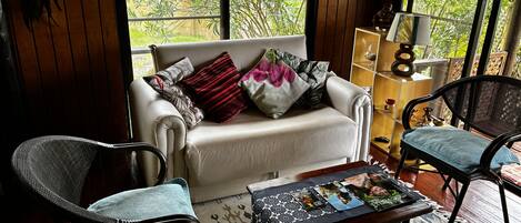 Un espacio de sala acogedor con un sofá, dos sillones, una mesita de centro y una estantería.