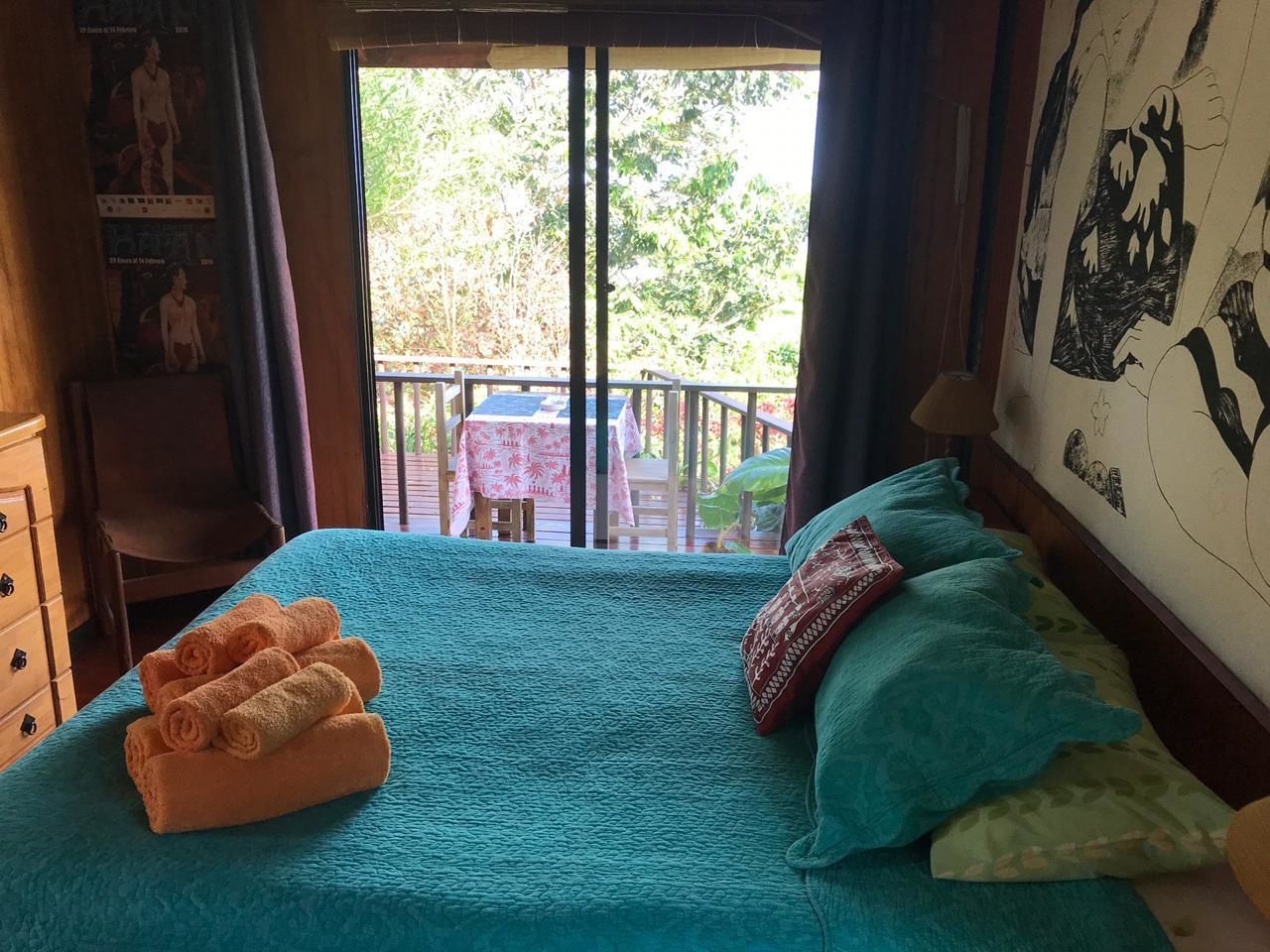 Un dormitorio con cama, una silla, una mesa con mantel y un balcón con mesa y sillas.