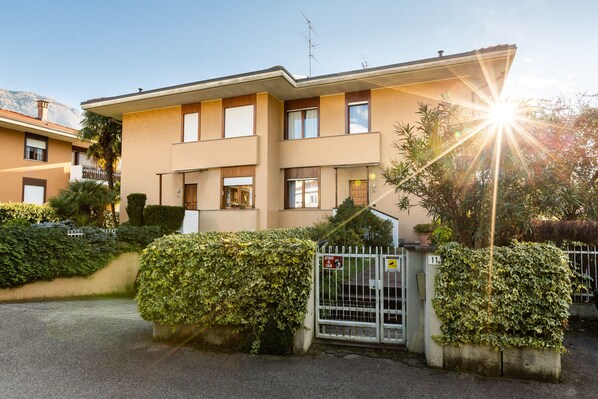 A two-story building with a gated entrance, a visible sign indicating a care facility, and a clear sky. - Villa Mary with garden (Arco)