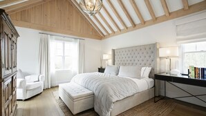 A bedroom with a large bed, a desk, and a chair.