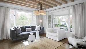 A modern living room with a grey sofa, white armchair, and a glass coffee table.