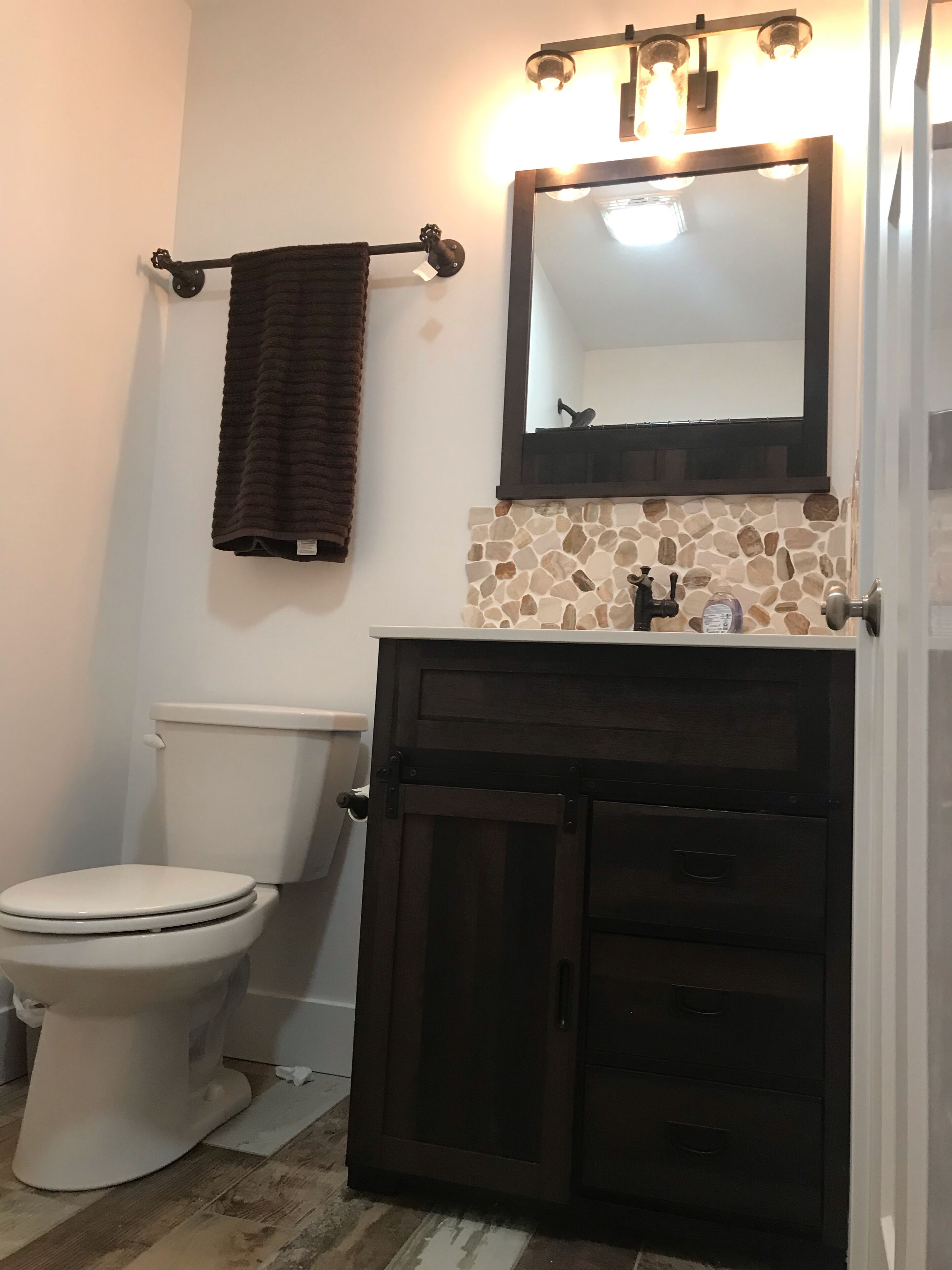 A bathroom with a toilet, a vanity with a mirror, and a towel rack.