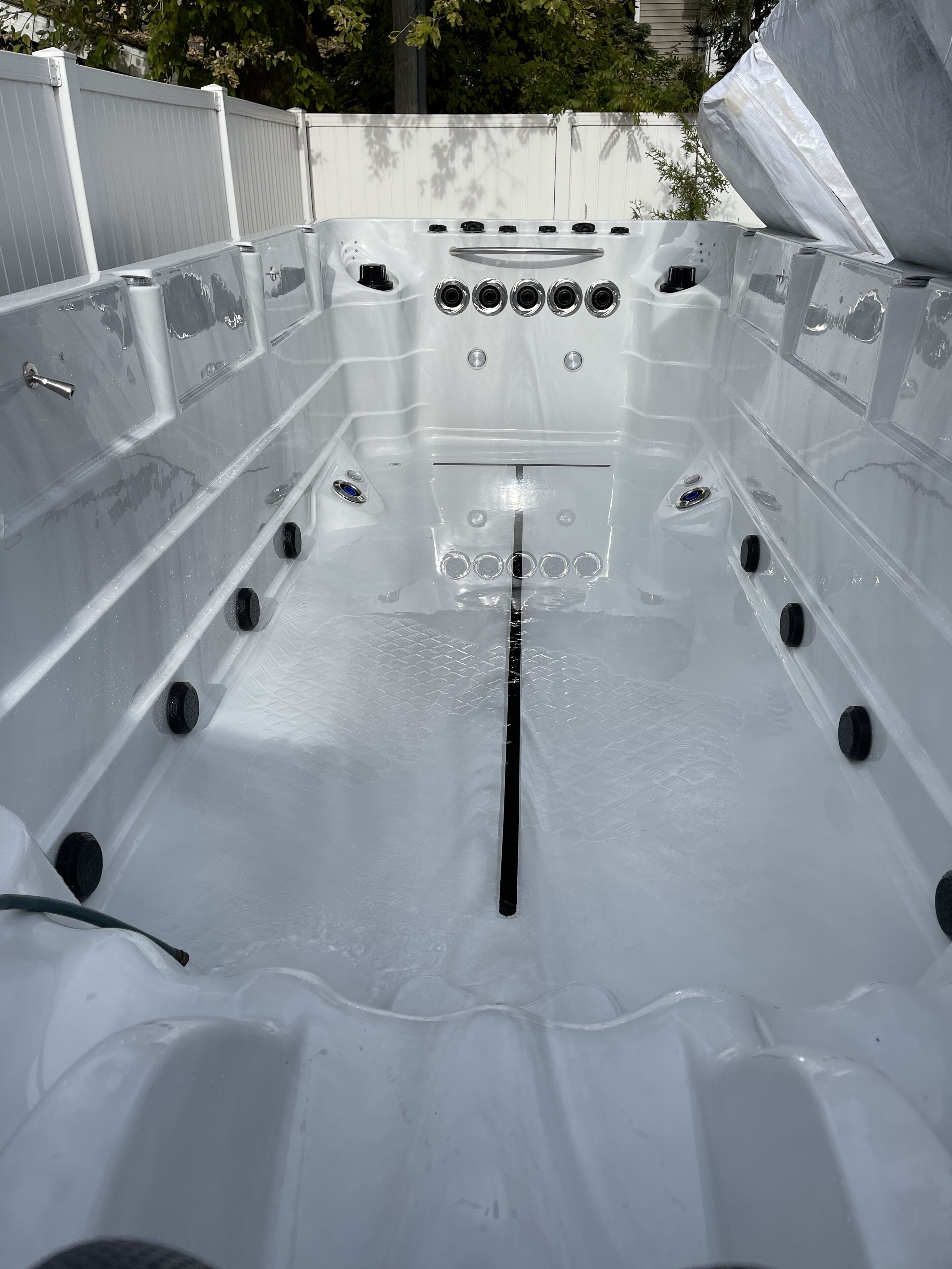 Ein Whirlpool mit zahlreichen Düsen und einer Bedienkonsole, umgeben von einer weißen Außenverkleidung.
