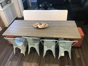 Un coin repas avec une table en bois, quatre chaises bleu clair et un saladier rempli de viennoiseries posé sur la table.