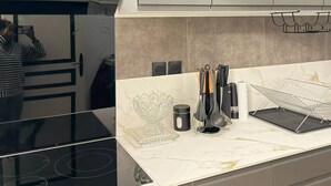 Een keuken met een zwart fornuis, witte kastjes en een marmeren spatwand.