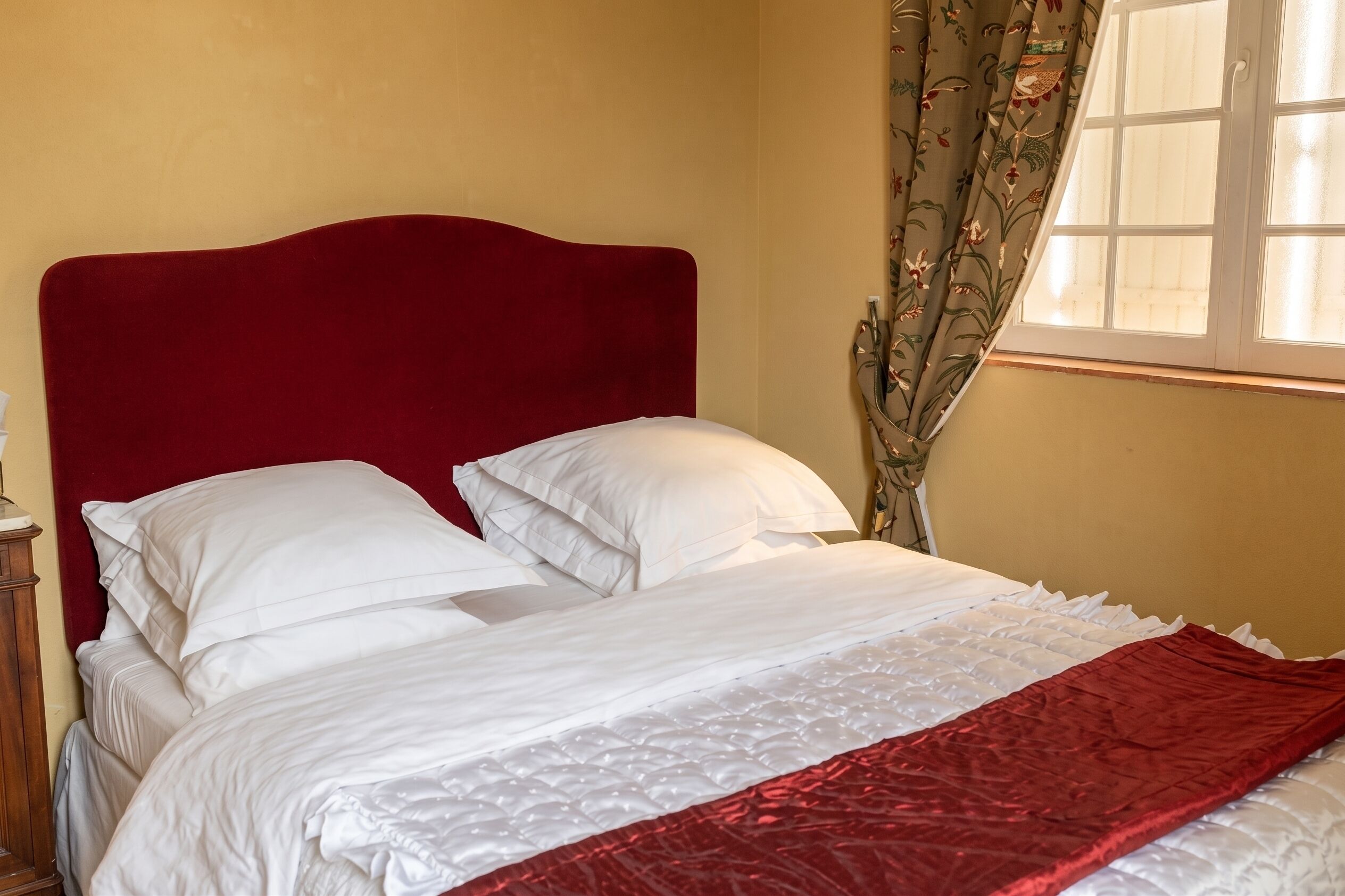 A bed with a red headboard, white bedding, and a red blanket.