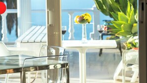 A glass table with a white chair, a white table, and a glass of wine on a balcony with a view of the sea. -  Relaxing villa. Heated pool. Luxurious views. Massage. (Santa Úrsula)