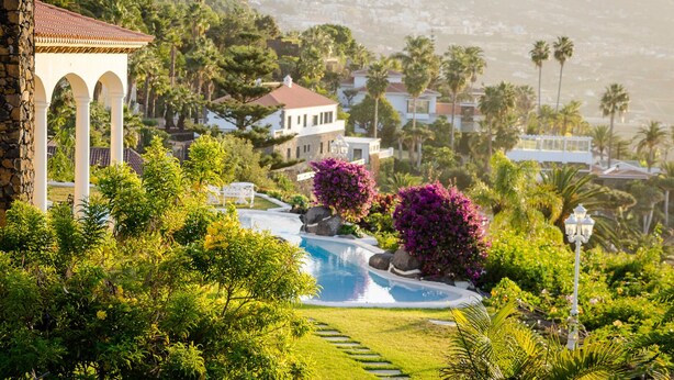 A residential area with a swimming pool, lush greenery, and houses with red-tiled roofs. -  Relaxing villa. Heated pool. Luxurious views. Massage. (Santa Úrsula)