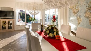A modern dining area with a white table, red runner, and a floral centerpiece. -  Relaxing villa. Heated pool. Luxurious views. Massage. (Santa Úrsula)