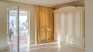 A room with a large white wardrobe, a glass door leading to an outdoor area with a table and chairs, and a floor lamp. -  Relaxing villa. Heated pool. Luxurious views. Massage. (Santa Úrsula)