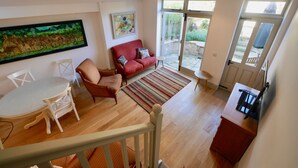 A spacious living area with a red sofa, white chairs, a dining table, and a kitchen area.