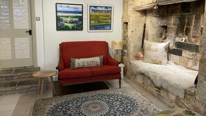 A cozy living room with a red sofa, a patterned rug, and a stone fireplace.