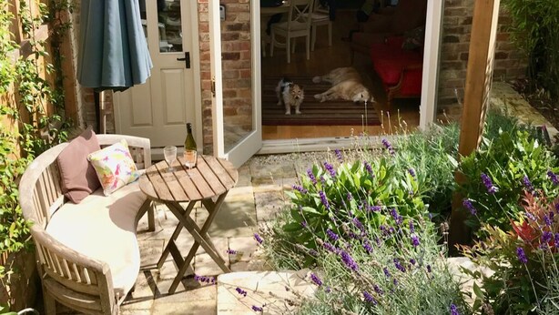 A brick house with a patio, a wooden table, and a chair.