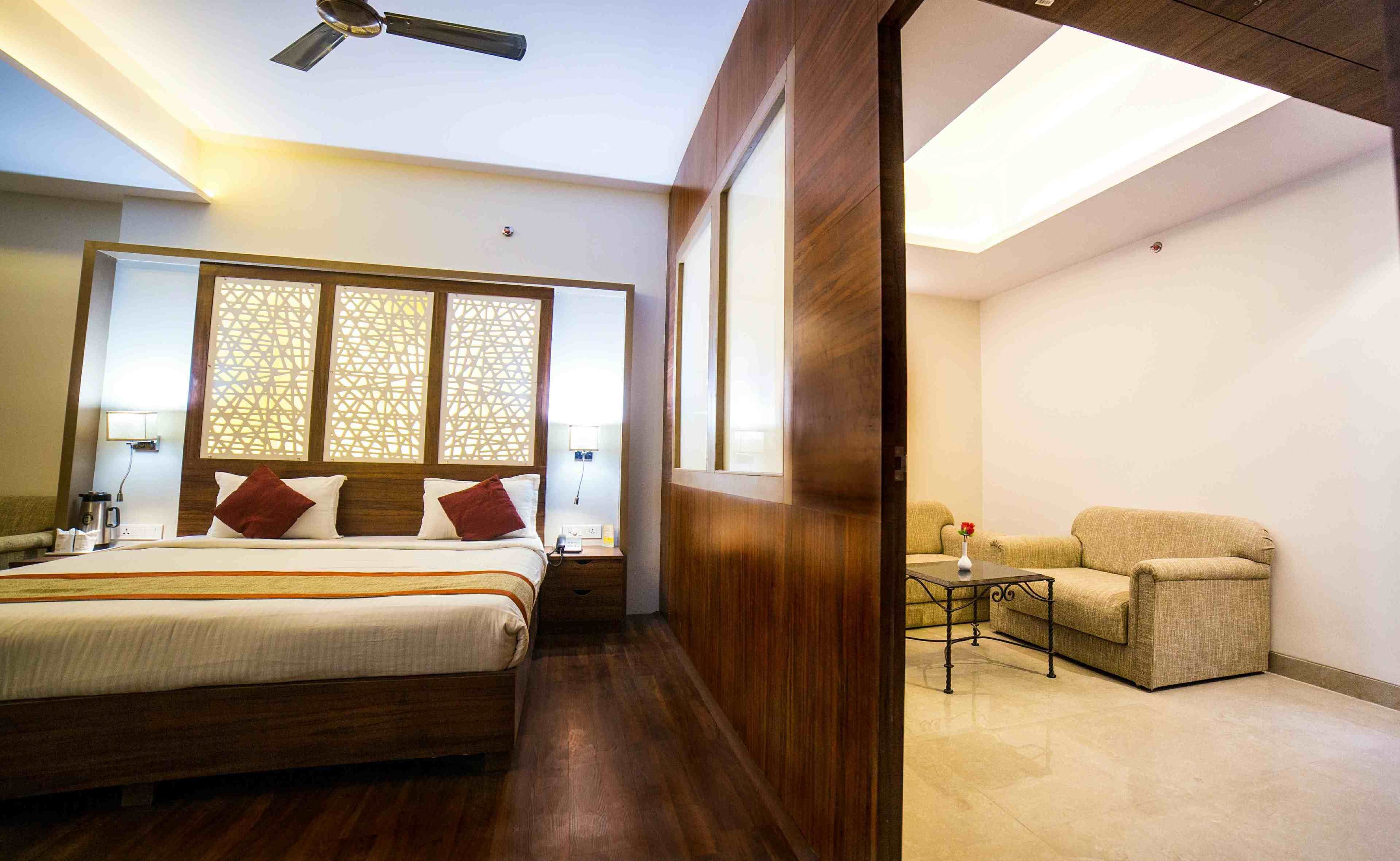A hotel room with a bed, bedside table, lamp, and a seating area with a table and chair.