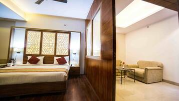 A hotel room with a bed, bedside table, lamp, and a seating area with a table and chair.