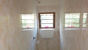 A small bathroom with a toilet, sink, and window. - Mali Guest House (Mombasa)