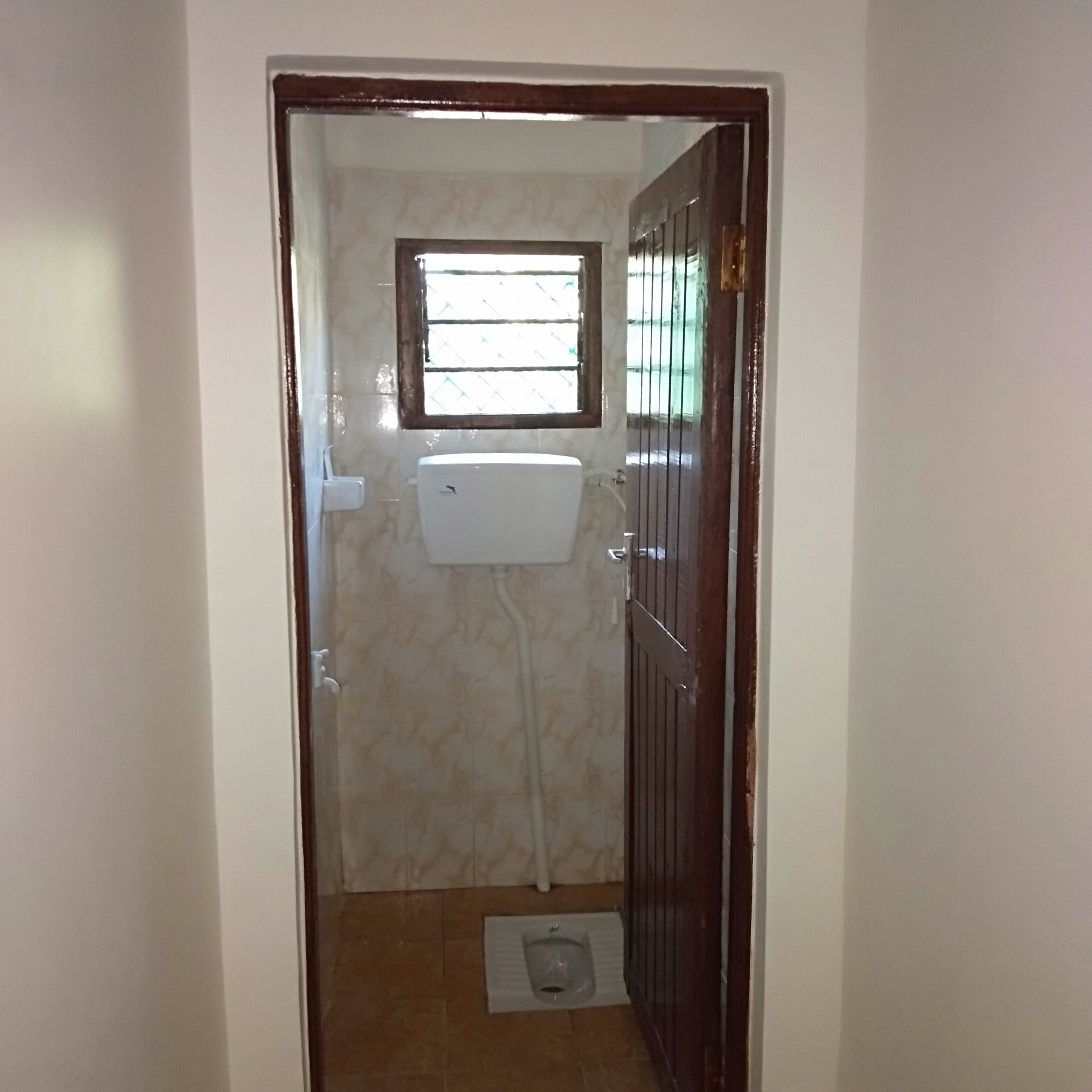 Un baño pequeño con ventana, inodoro y zona de ducha.