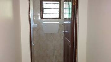 Un baño pequeño con ventana, inodoro y zona de ducha.