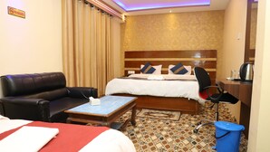 A hotel room with a bed, a desk, a chair, a coffee machine, and a trash bin. - Taplejung Hotel Pathivara (Taplejung)