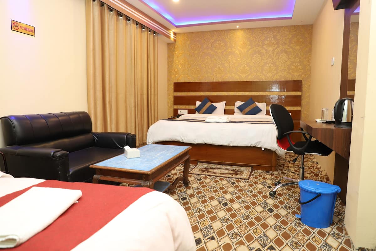 Habitación de hotel con cama, escritorio, silla, cafetera y cubo de basura.
