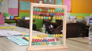 A wooden abacus with colorful beads on a table in a classroom setting. - Taplejung Hotel Pathivara (Taplejung)