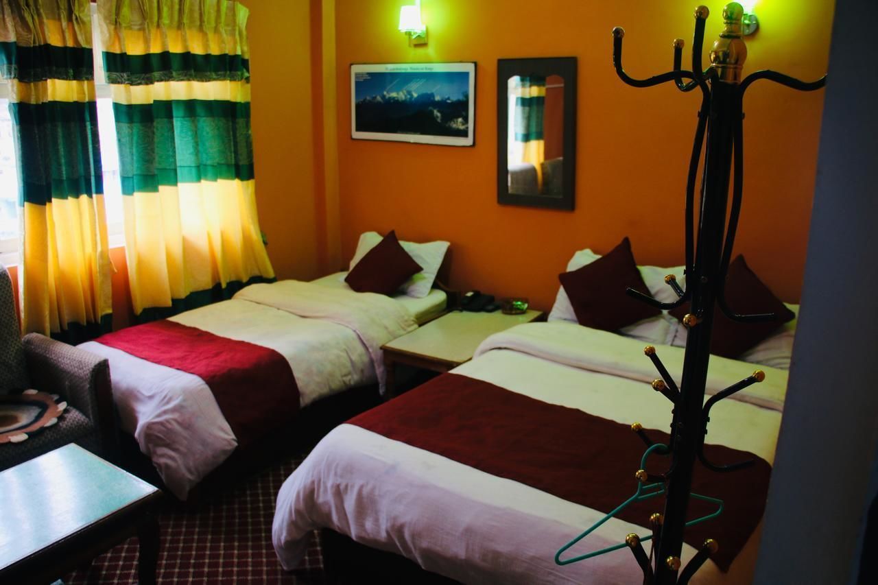 A hotel room with two beds, a small table, and a coat rack.