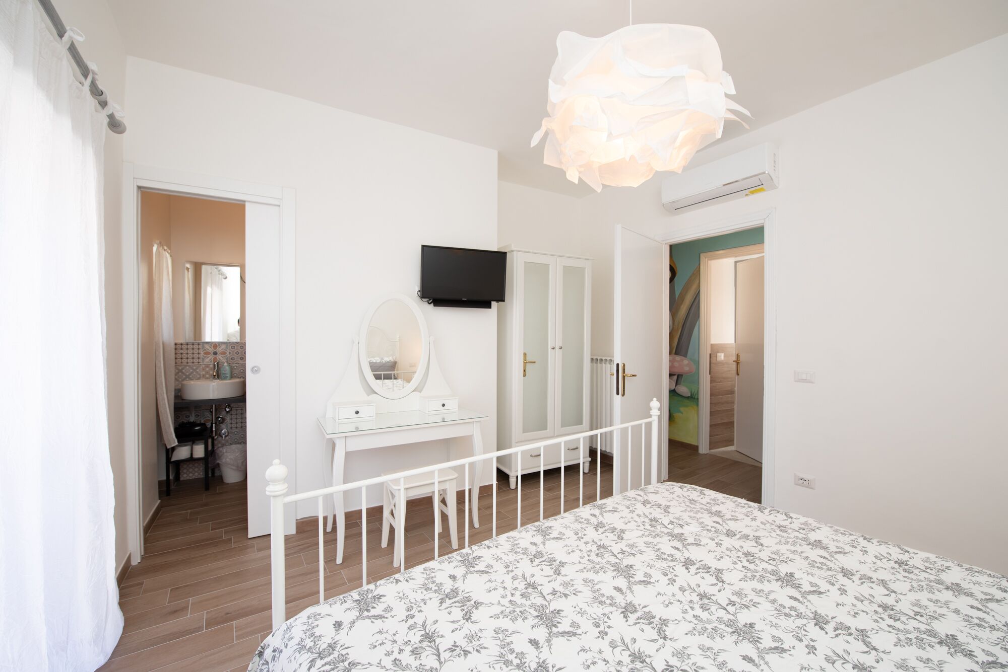 A bedroom with a bed, a dresser, a mirror, and a television.