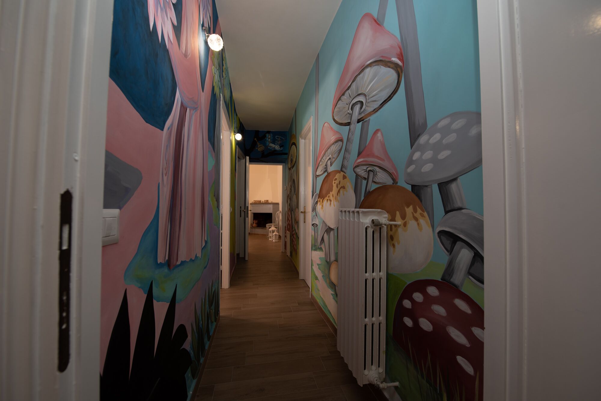 A narrow hallway with vibrant, colorful murals on the walls depicting mushrooms and abstract shapes.