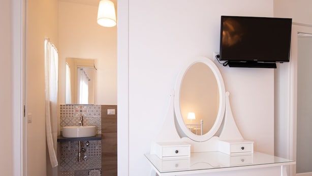 A white vanity with a mirror and a television mounted on the wall.
