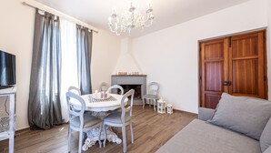 A cozy living room with a fireplace, a dining table with chairs, a sofa, and a television.