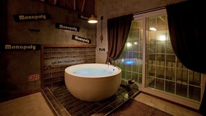 A spa room with a large bathtub, wooden wall tiles, and a sign indicating a cafe. - Monopoly Pension (Gyeongju)