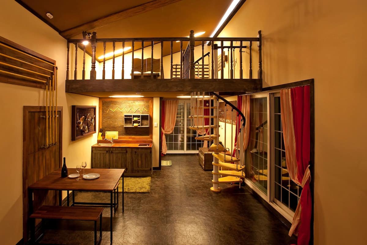 A cozy interior with a dining area, kitchen, and a staircase leading to an upper level.