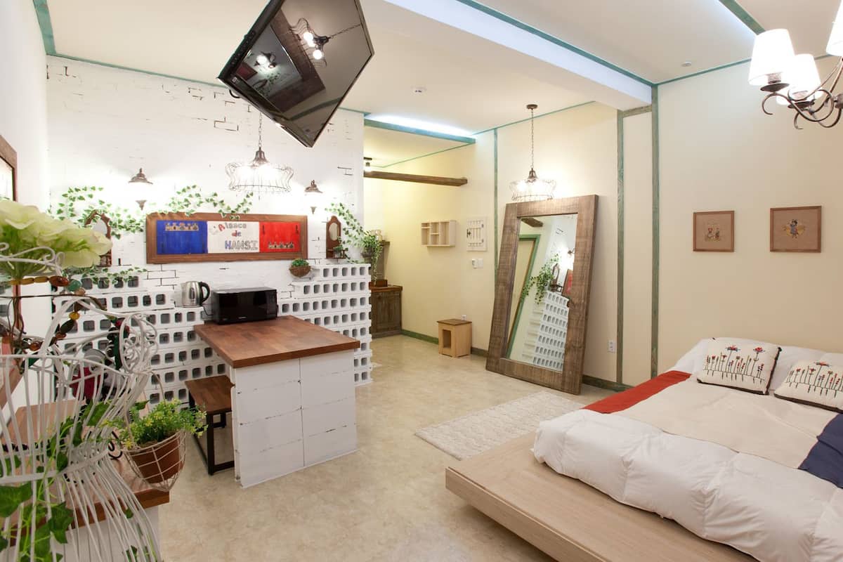 A bedroom with a bed, a TV mounted on the wall, and a mirror.