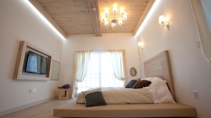 A bedroom with a wooden ceiling, a bed with multiple pillows, a small bedside table with a vase, and a window with curtains. - Monopoly Pension (Gyeongju)