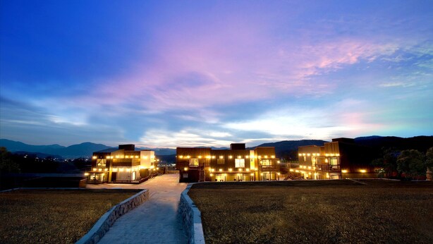 A modern hotel with a central courtyard, multiple guest rooms, and a view of distant mountains. - Monopoly Pension (Gyeongju)