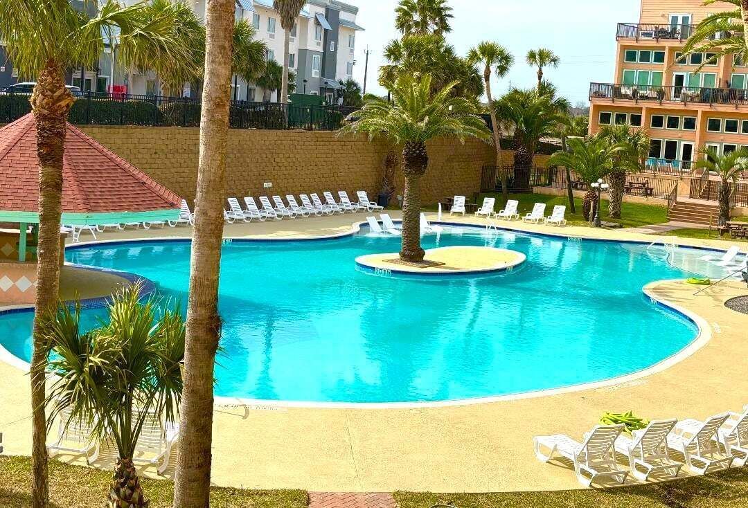 Una piscina con sillas de descanso y palmeras.