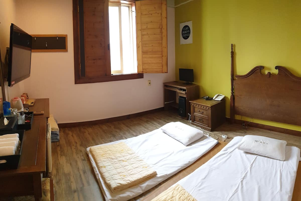 A room with a bed, a desk, a chair, a television, and a window.