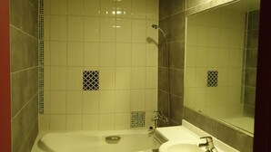 Un bagno con una vasca, un lavandino e uno specchio.