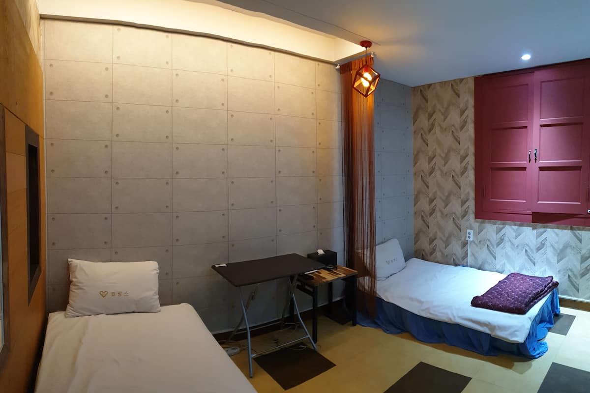 A hotel room with two beds, a desk, and a wardrobe.